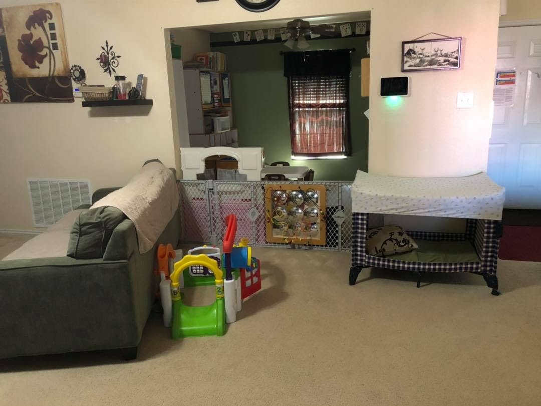 Living room with a sofa, playpen, and baby changing table