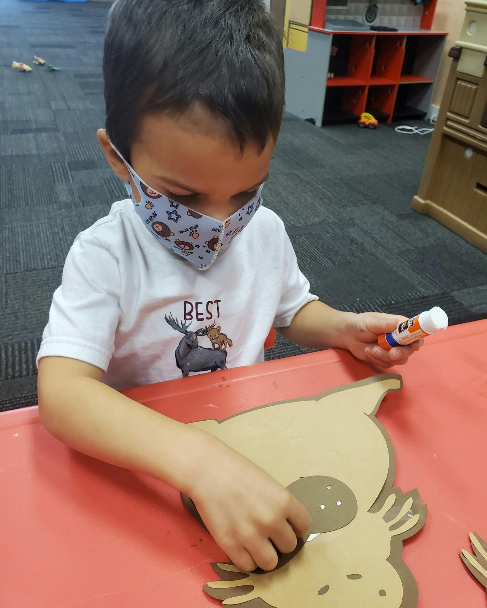 Child in a mask gluing a craft