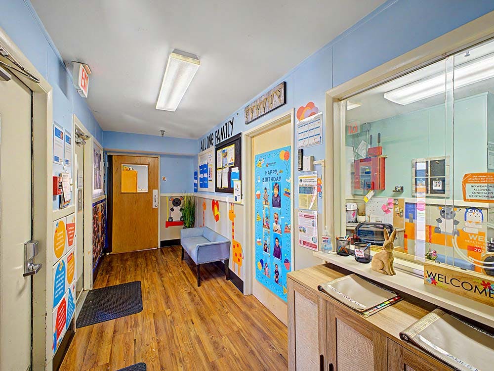 Hallway with wood floors, blue walls, a bench, and a window into an office