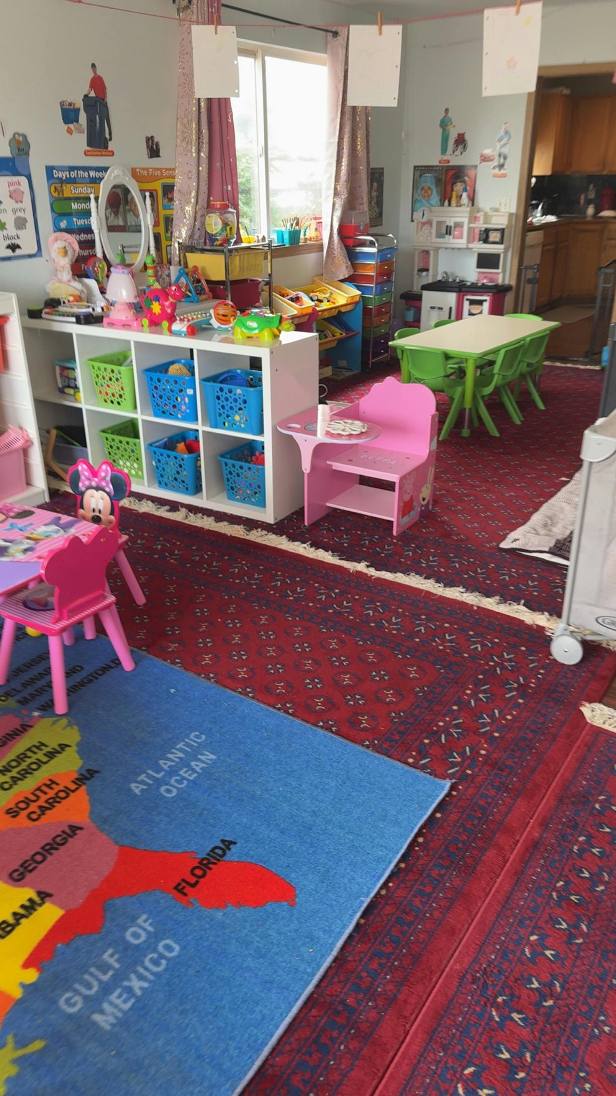 Playroom with colorful toys, small tables, and a map rug