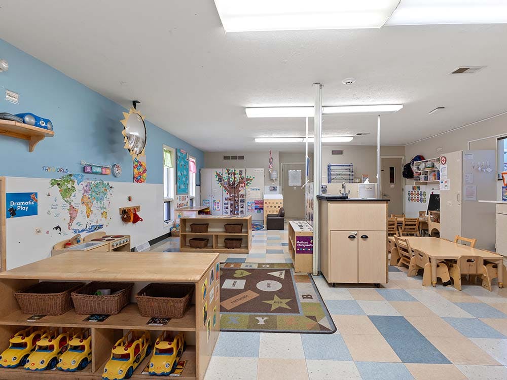 Classroom with children's furniture, shelves with toys, and wall decorations