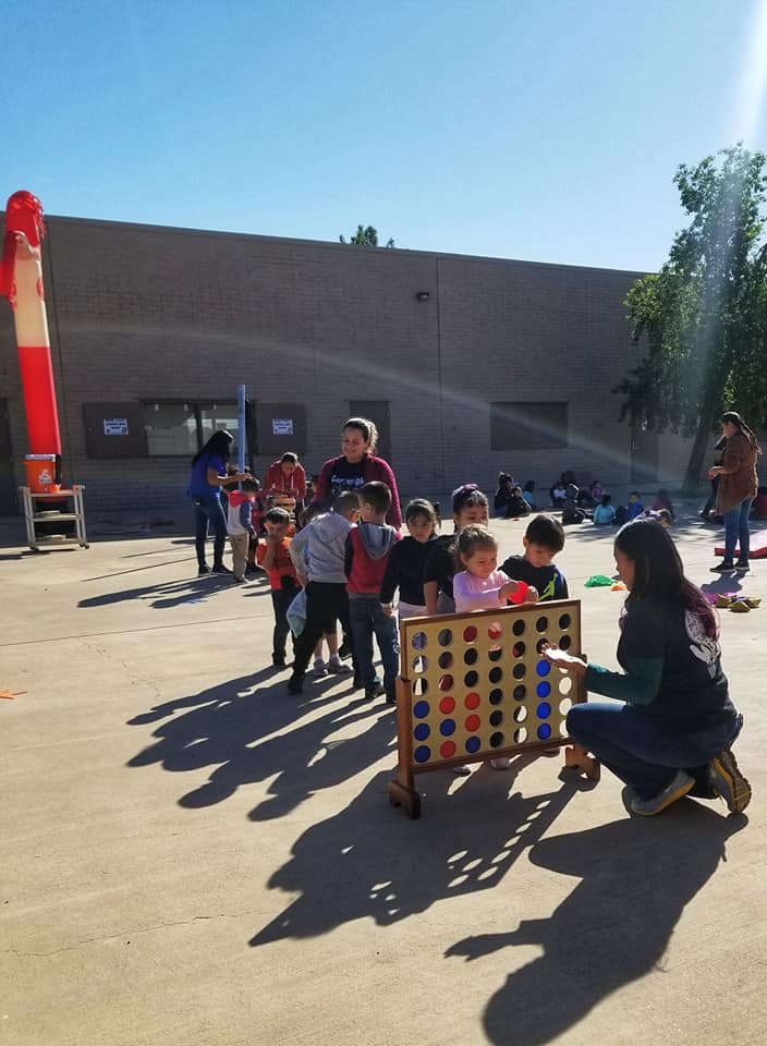 Person and children playing a giant Connect Four game outdoors