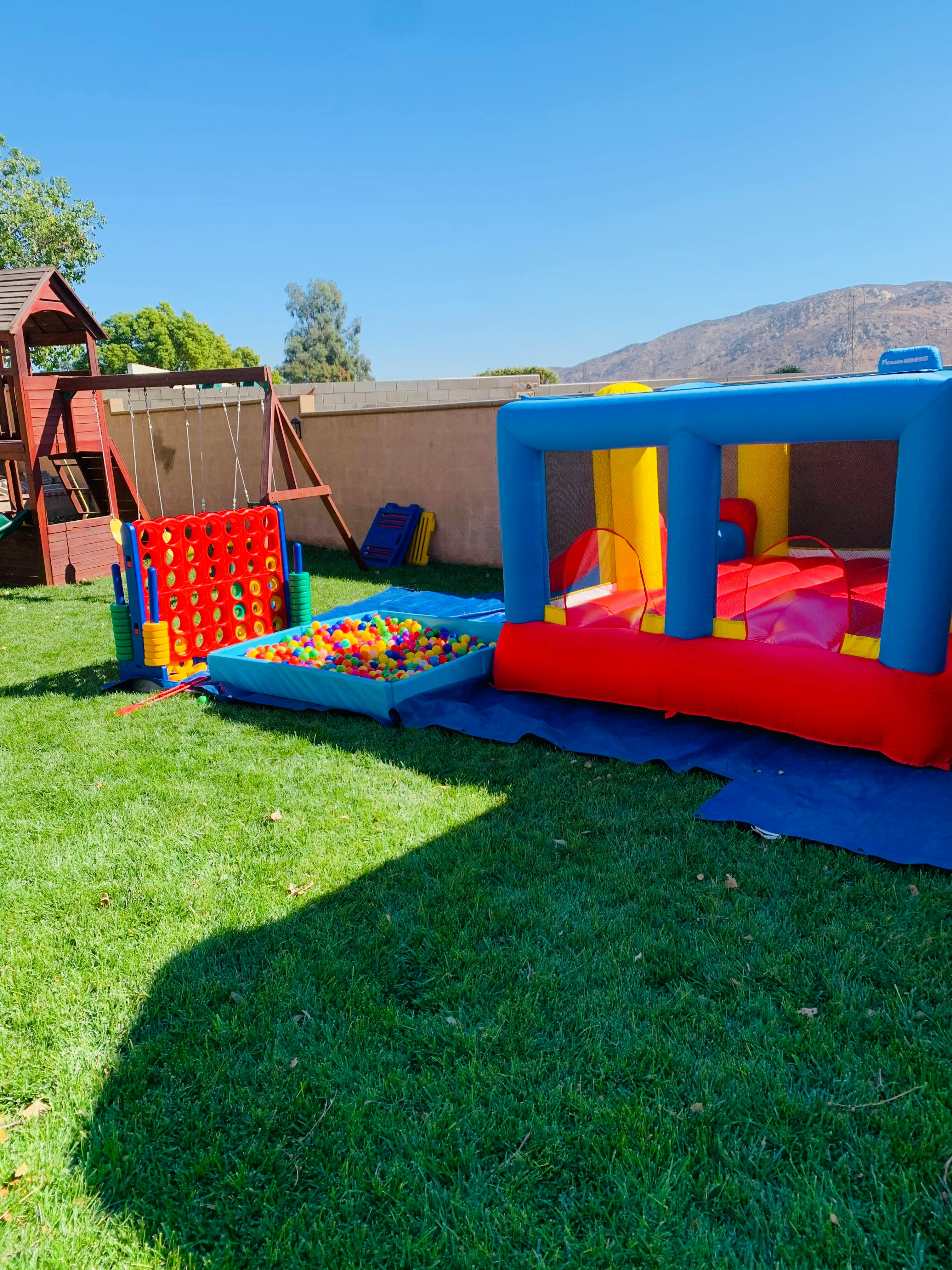 Inflatable bounce house, ball pit, and giant Connect Four game on grass