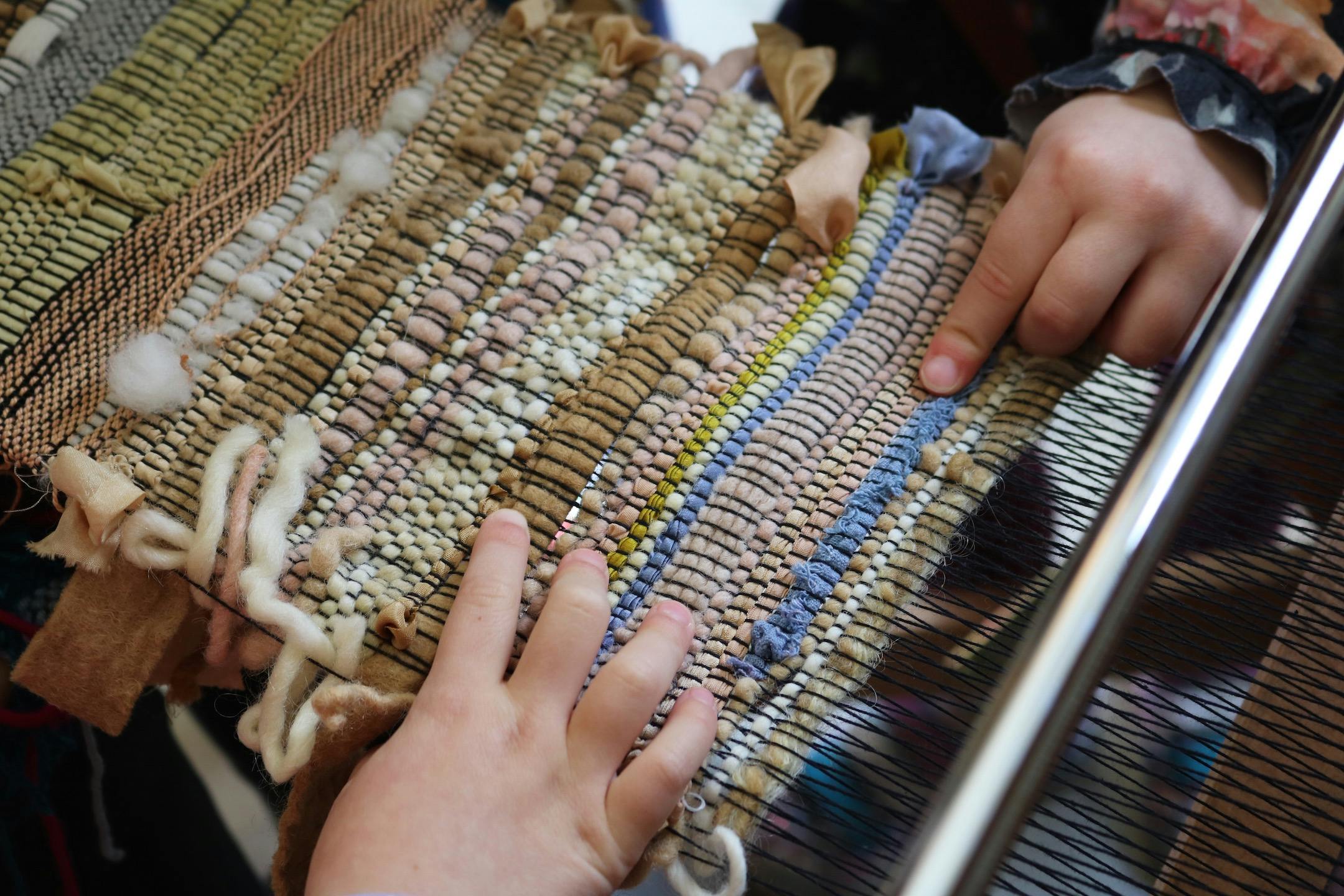 Two hands touching a piece of woven fabric