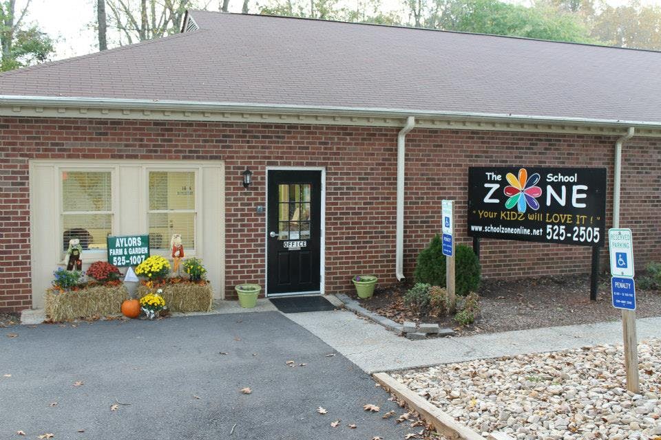 Brick building with a black door and a sign for The School Zone