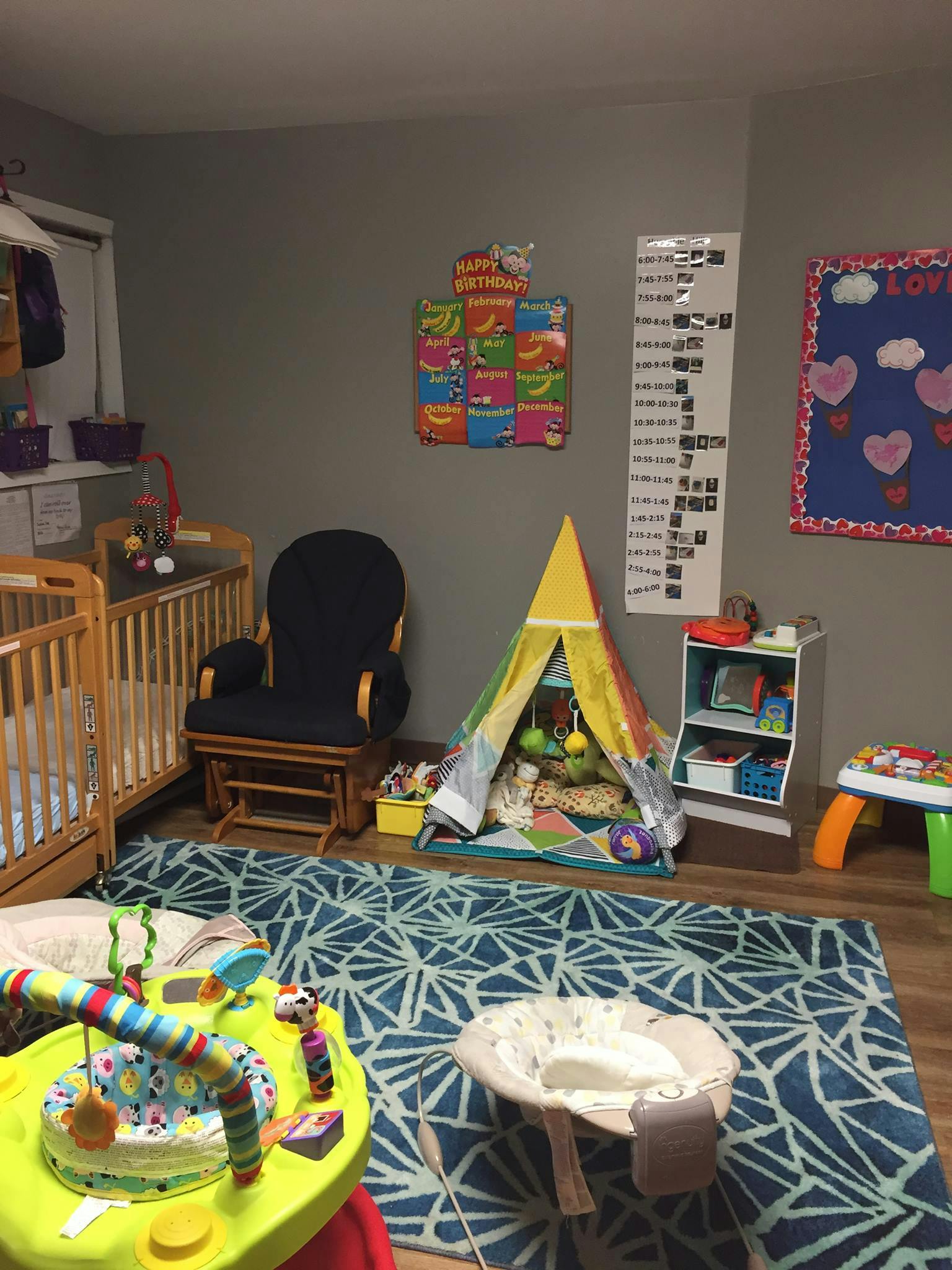 Nursery room with cribs, a rocking chair, a play tent, and baby activity items