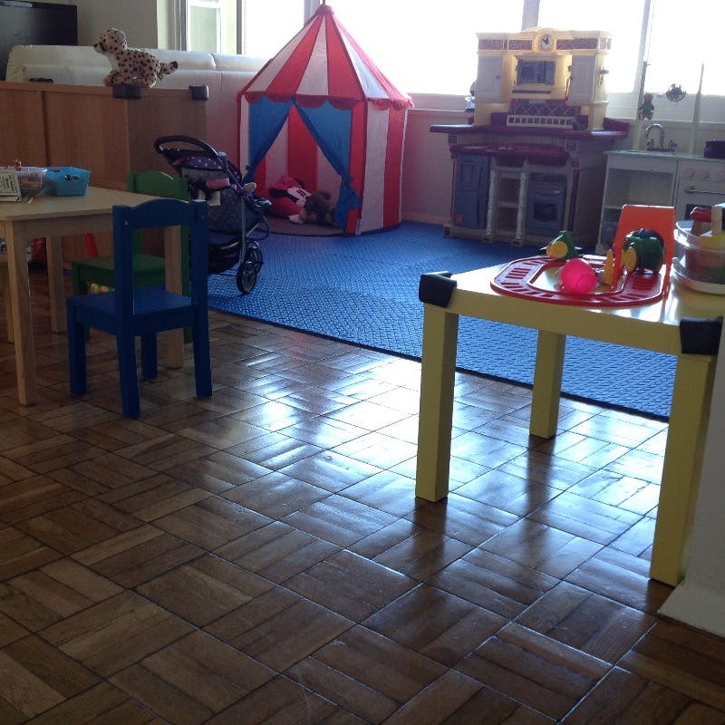 Playroom with small tables, chairs, and a red and white play tent