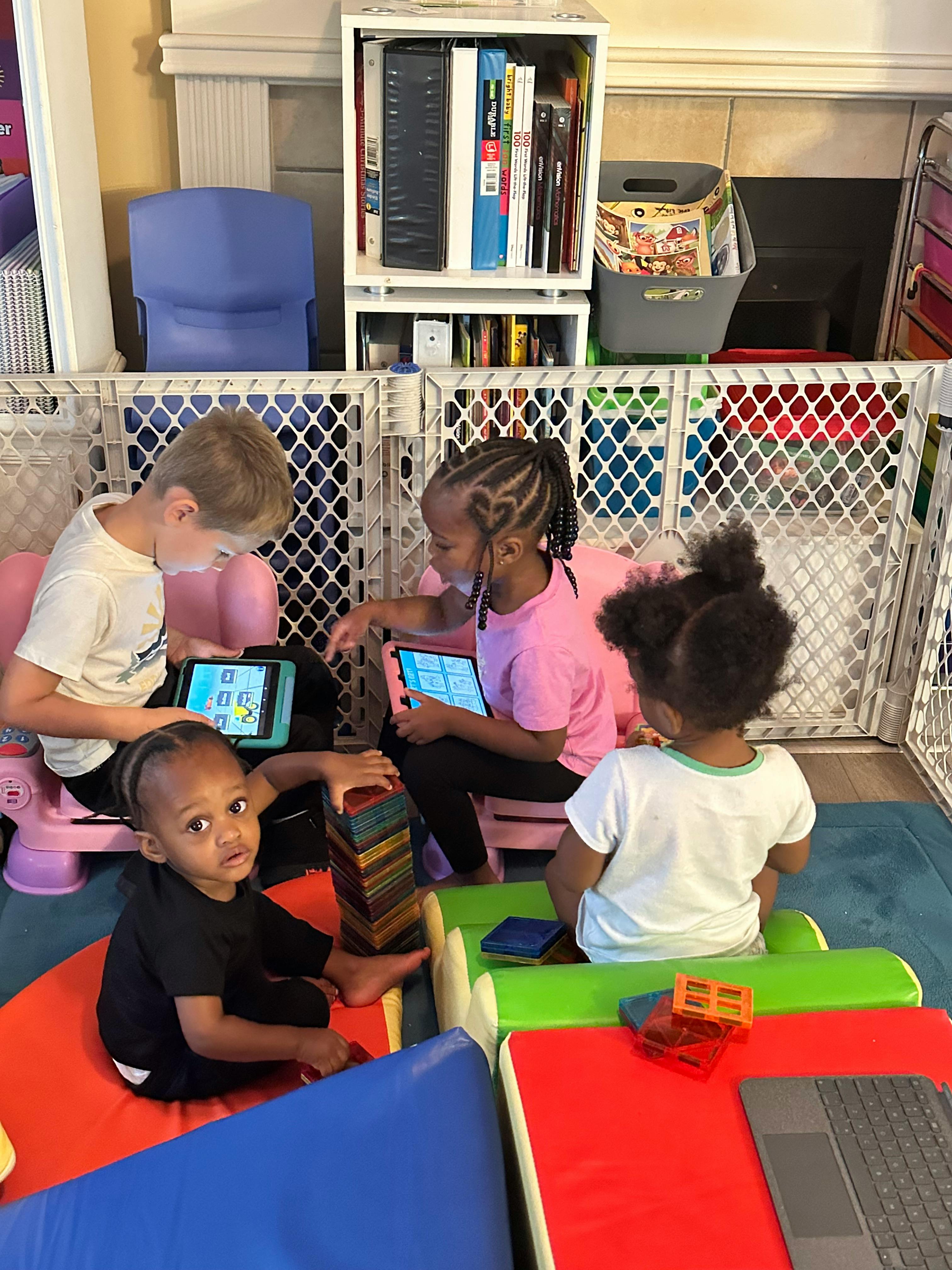 Three children playing with tablets in a play area