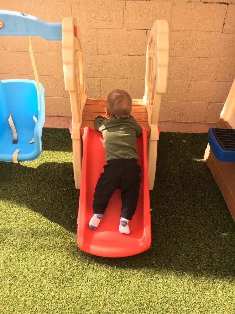 Child climbing up a red slide on a playground