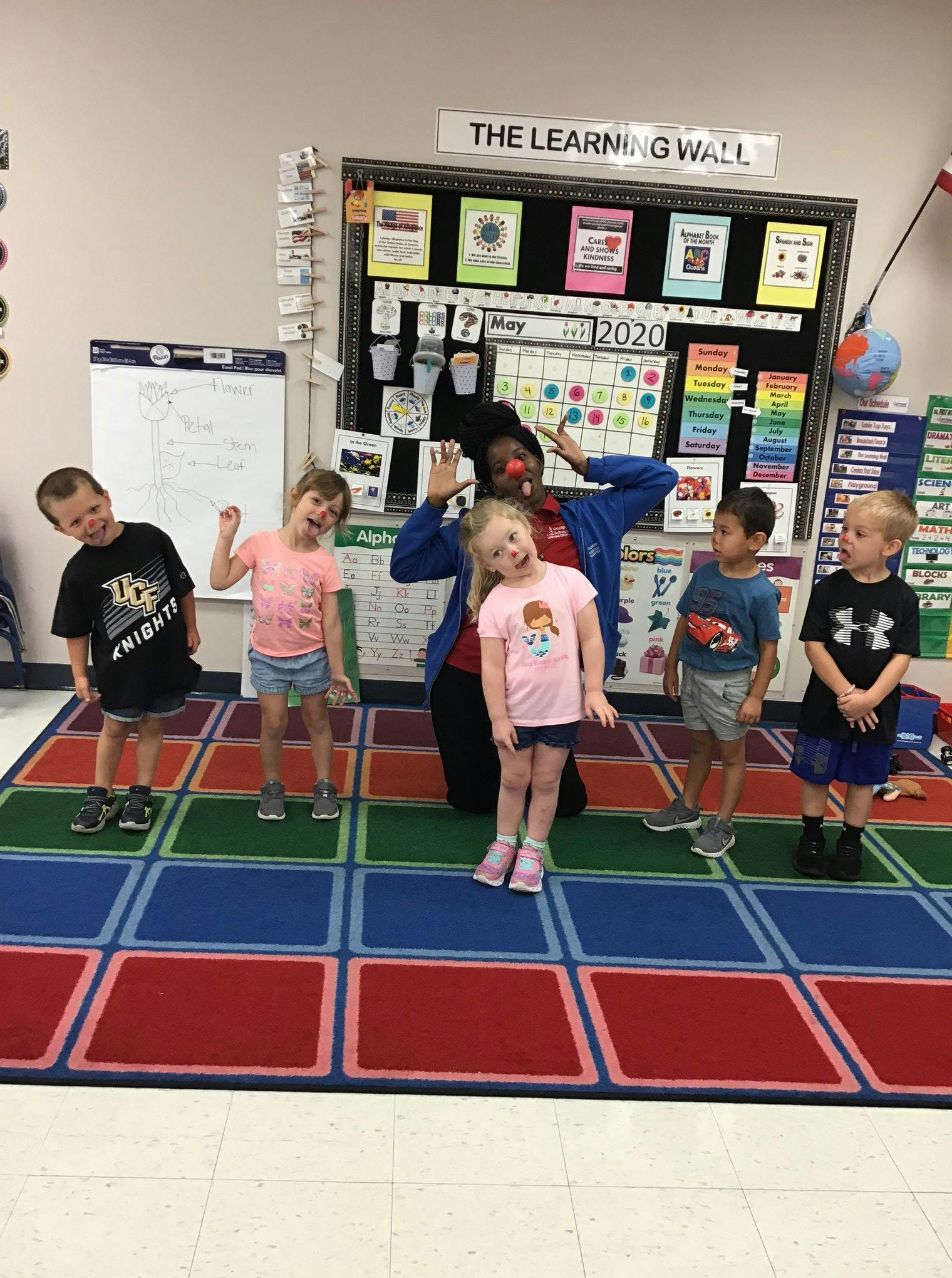 Person in clown nose with four children in a classroom