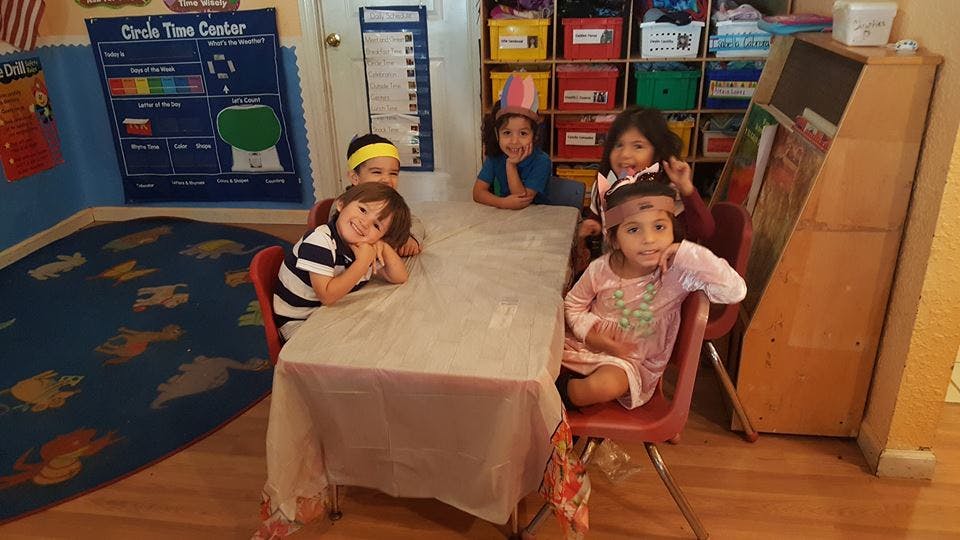 Four children sitting at a table in a classroom