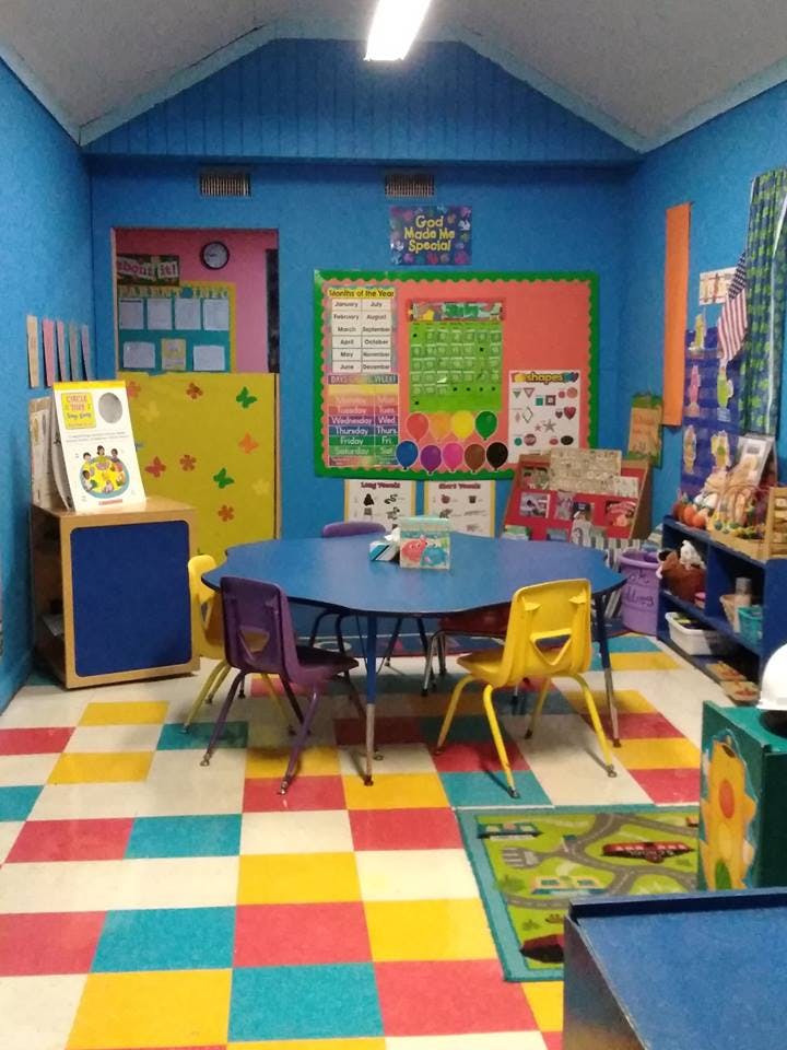 Classroom with blue walls, colorful floor, blue table, and small chairs