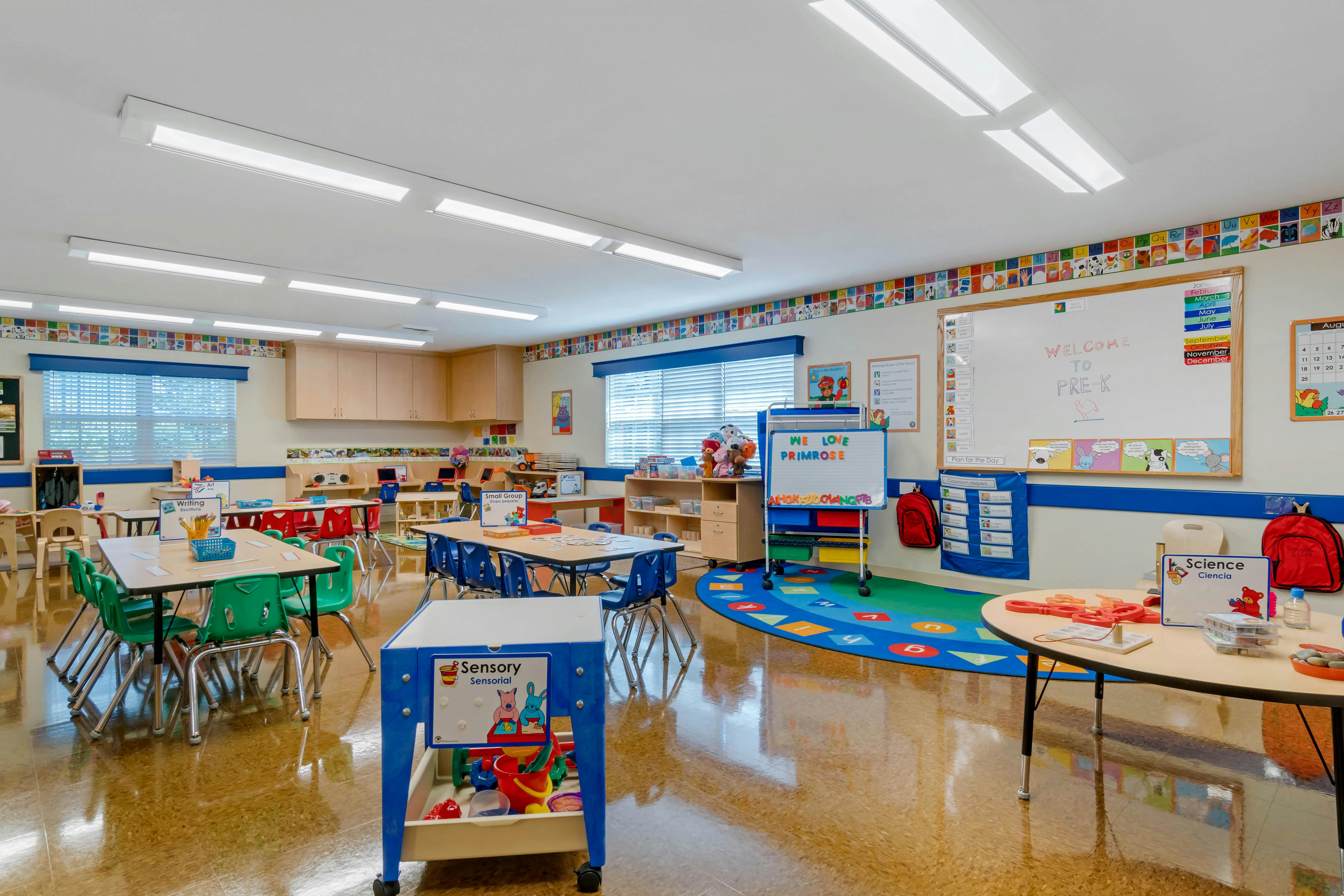 Empty classroom with small tables and chairs, whiteboards, and learning materials