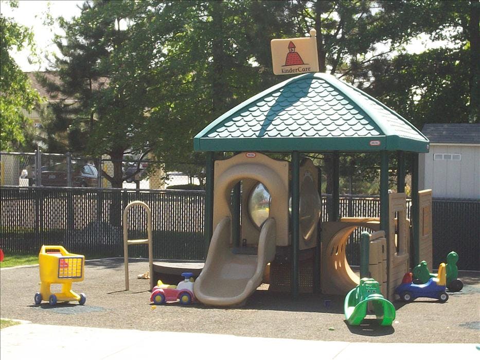 A childcare playground with a play structure, slide, and several ride-on toys