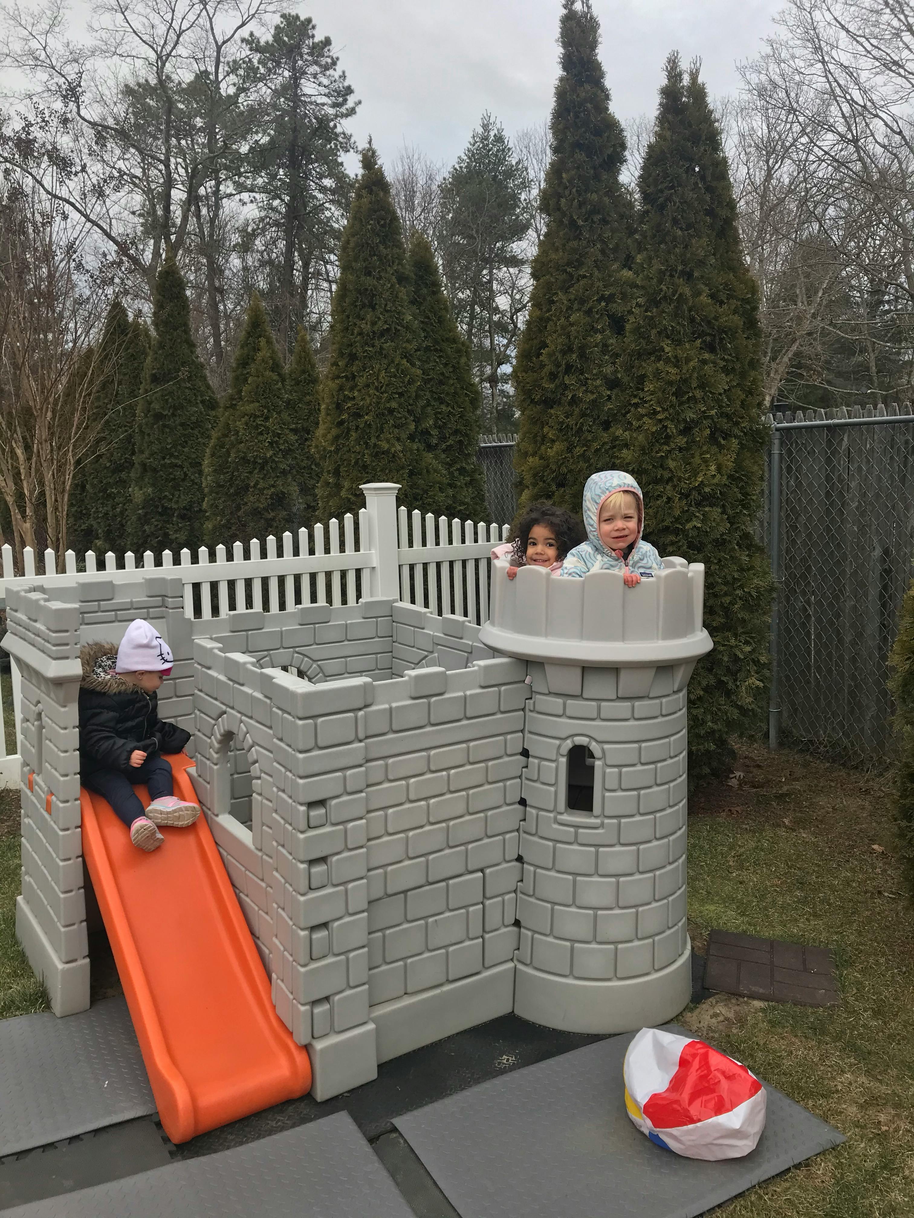 Children playing on a castle-themed playset with a slide