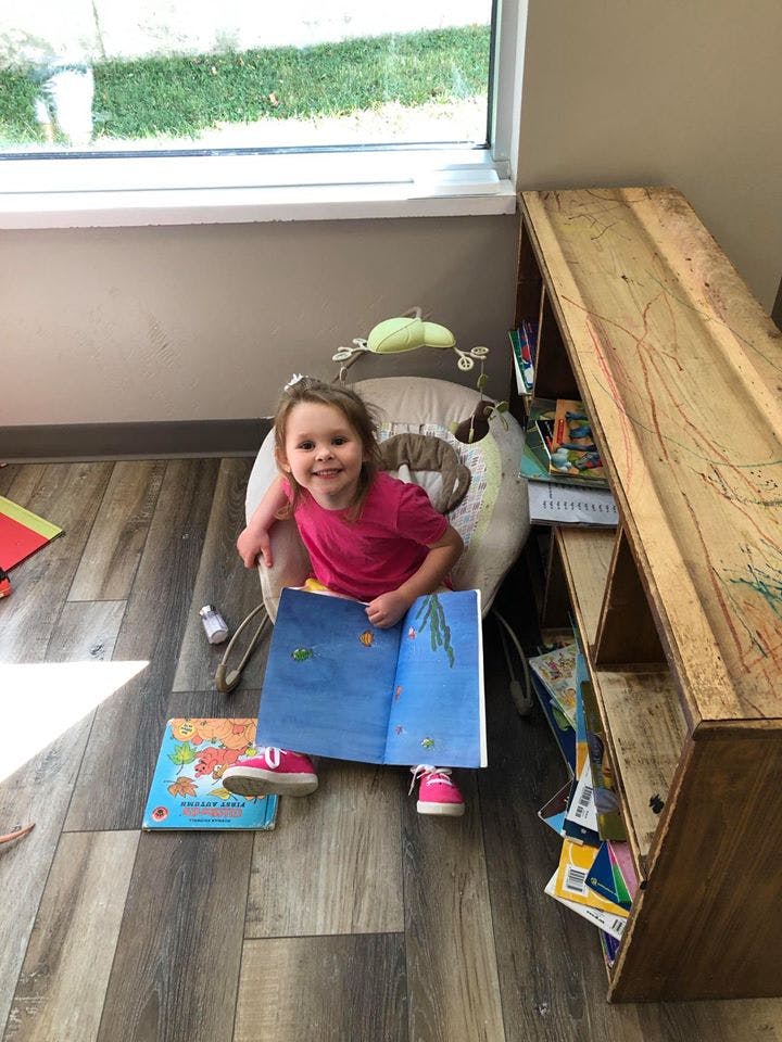 Child sitting in a chair holding an open book