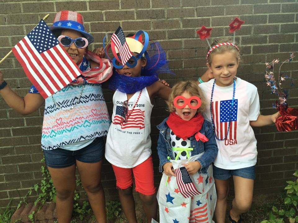 Four children in patriotic attire holding American flags