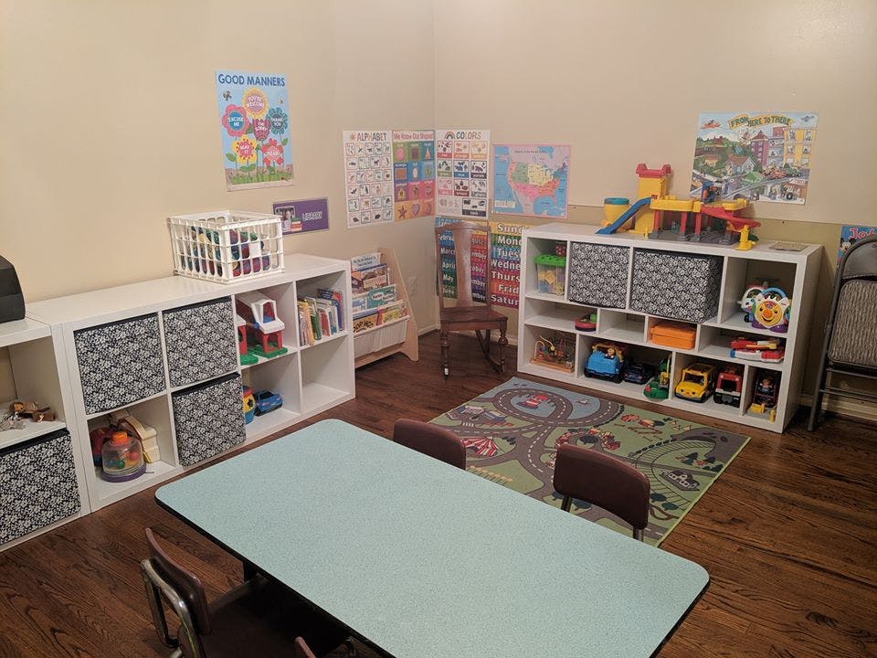 Playroom with shelves of toys and books, a rug, and a table with chairs