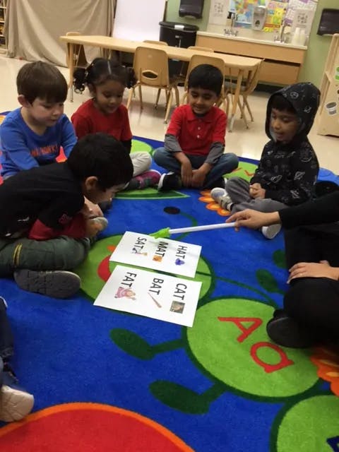 Children sitting on a rug looking at word cards