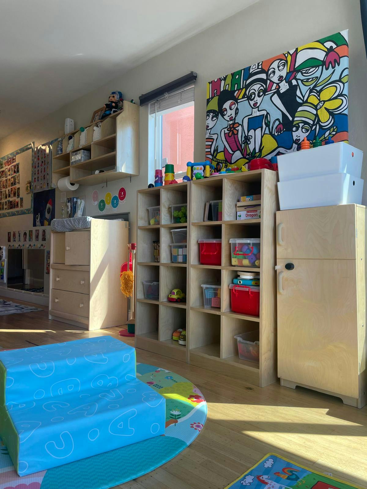 Playroom with shelves full of toys and a colorful mural on the wall