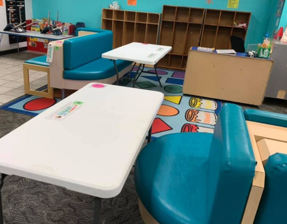 Empty classroom with tables, chairs, and cubbies