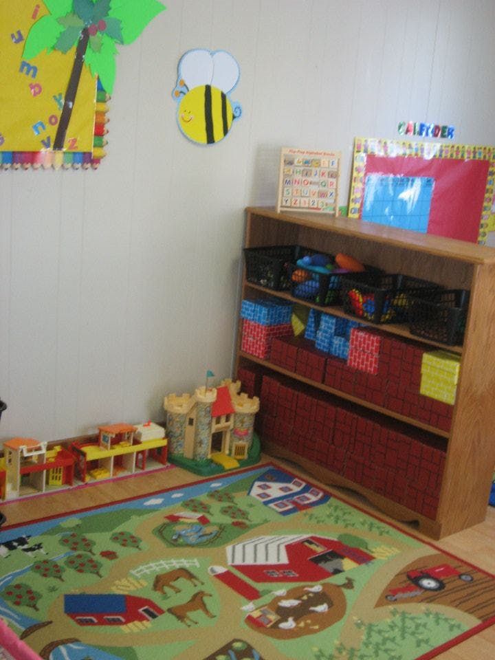 Playroom with a bookshelf, toy castle, and farm-themed rug