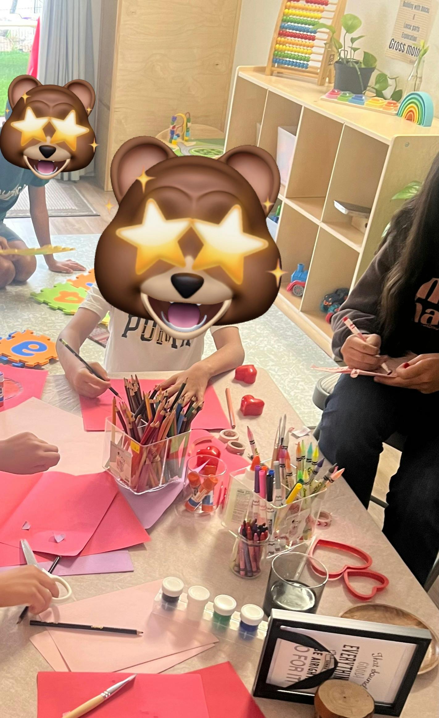 Children doing arts and crafts at a table with paper, crayons, and paint
