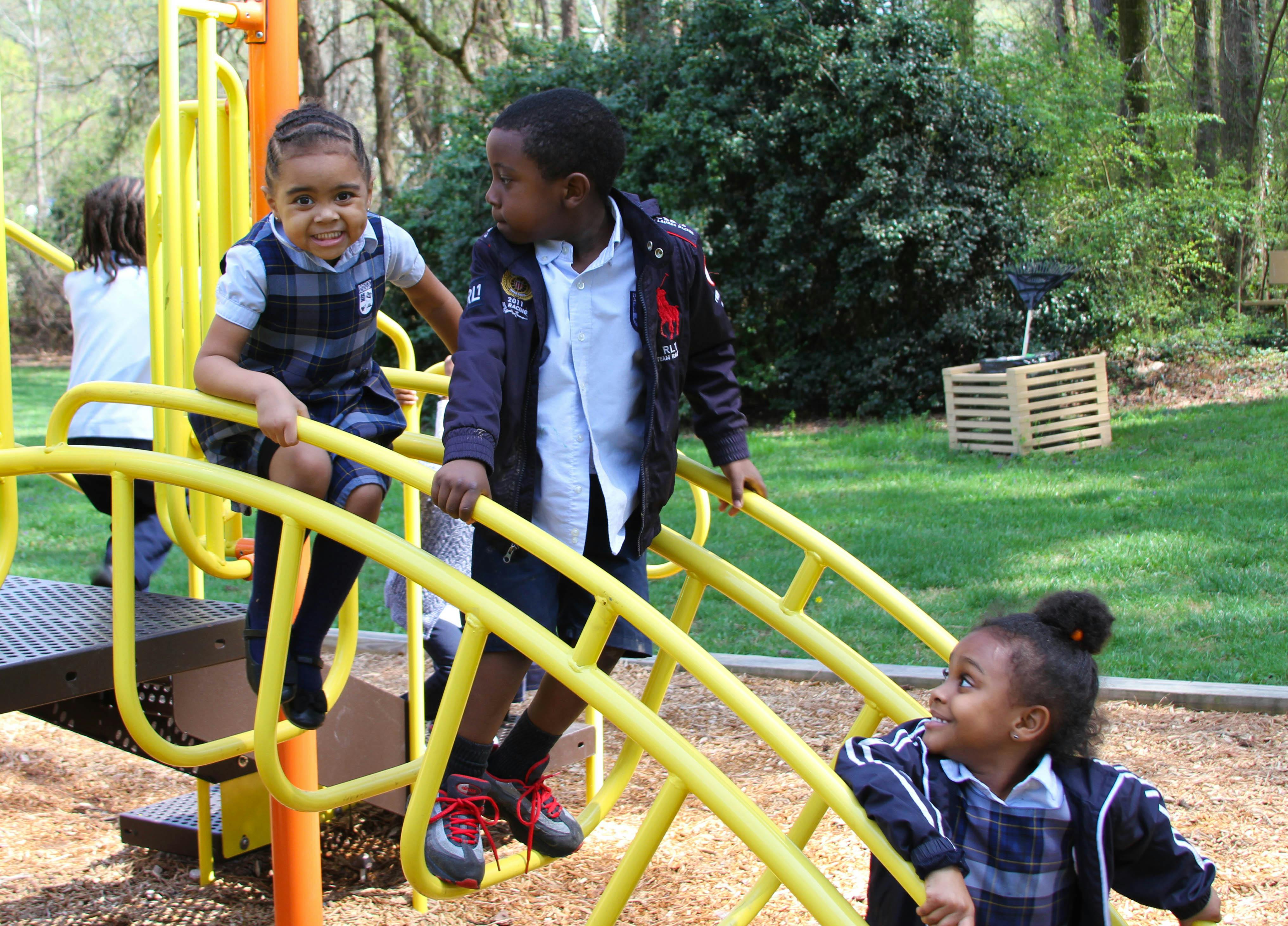 Three children playing on yellow playground equipment
