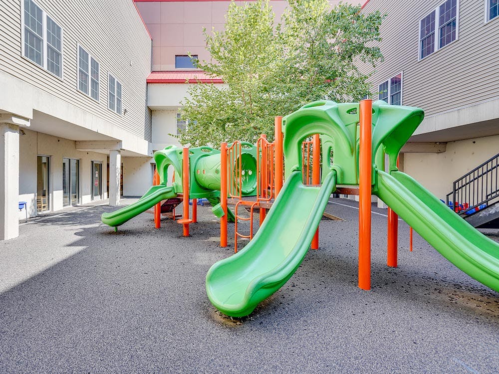 A green and orange playground with multiple slides and climbing structures
