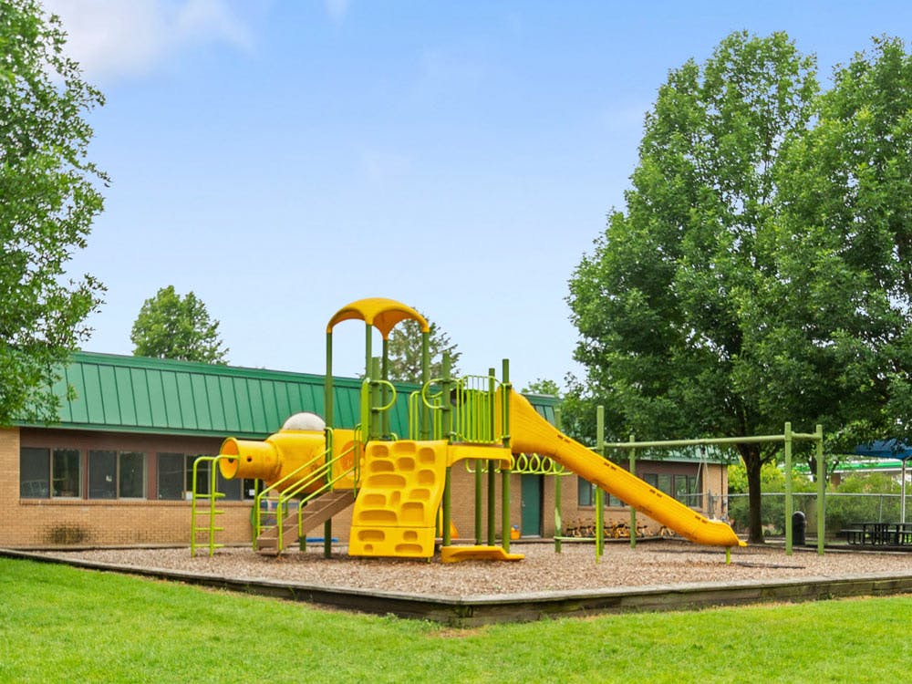 Yellow and green playground with a slide and climbing structures