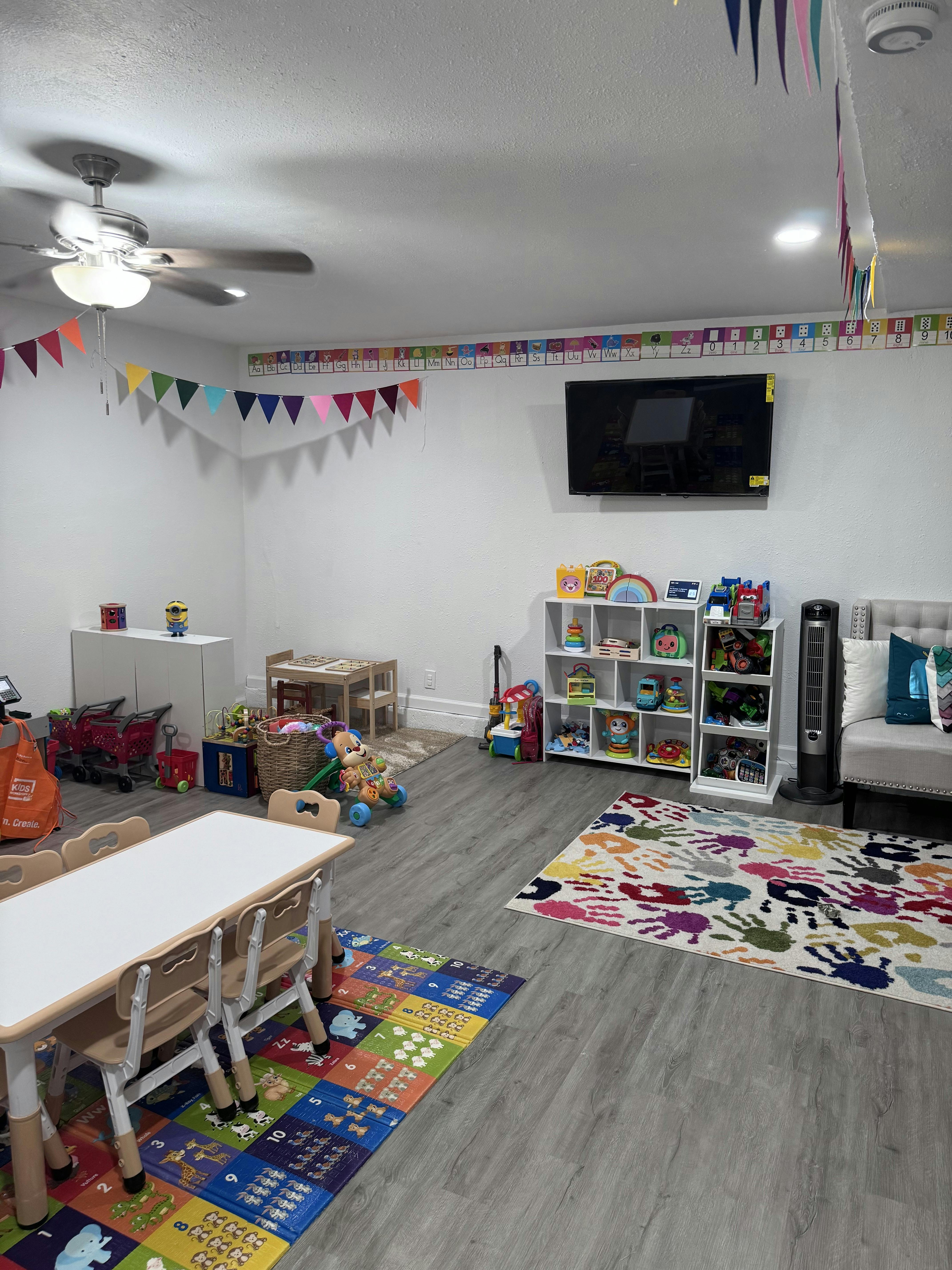 Playroom with small tables and chairs, shelves of toys, and colorful rugs