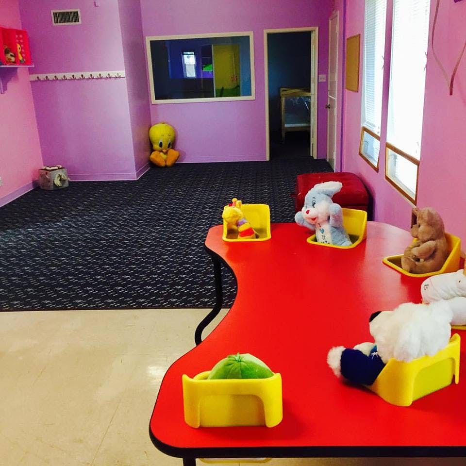 Stuffed animals sitting on a red table in a room with purple walls