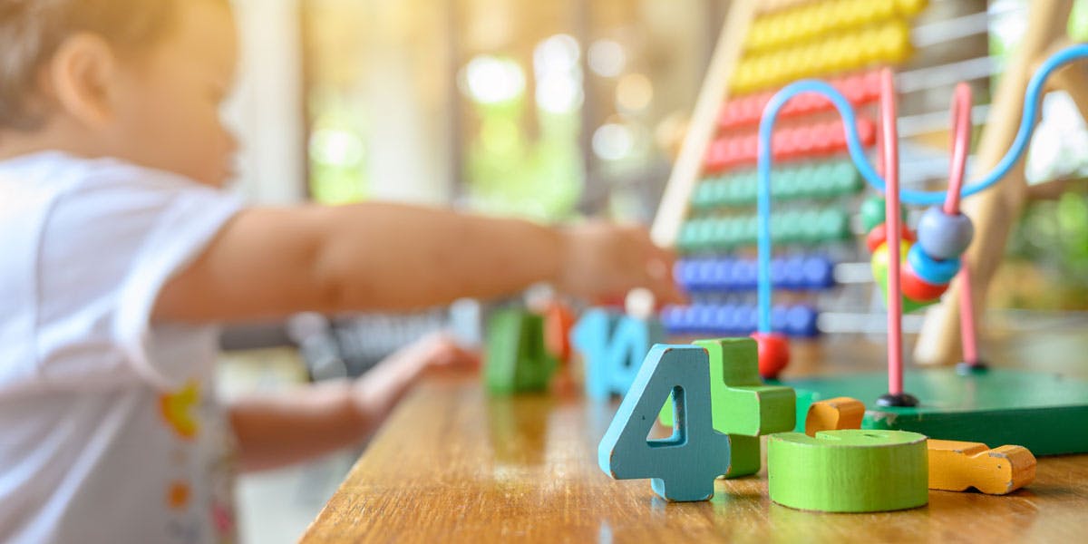 Child playing with wooden number blocks and an abacus toy