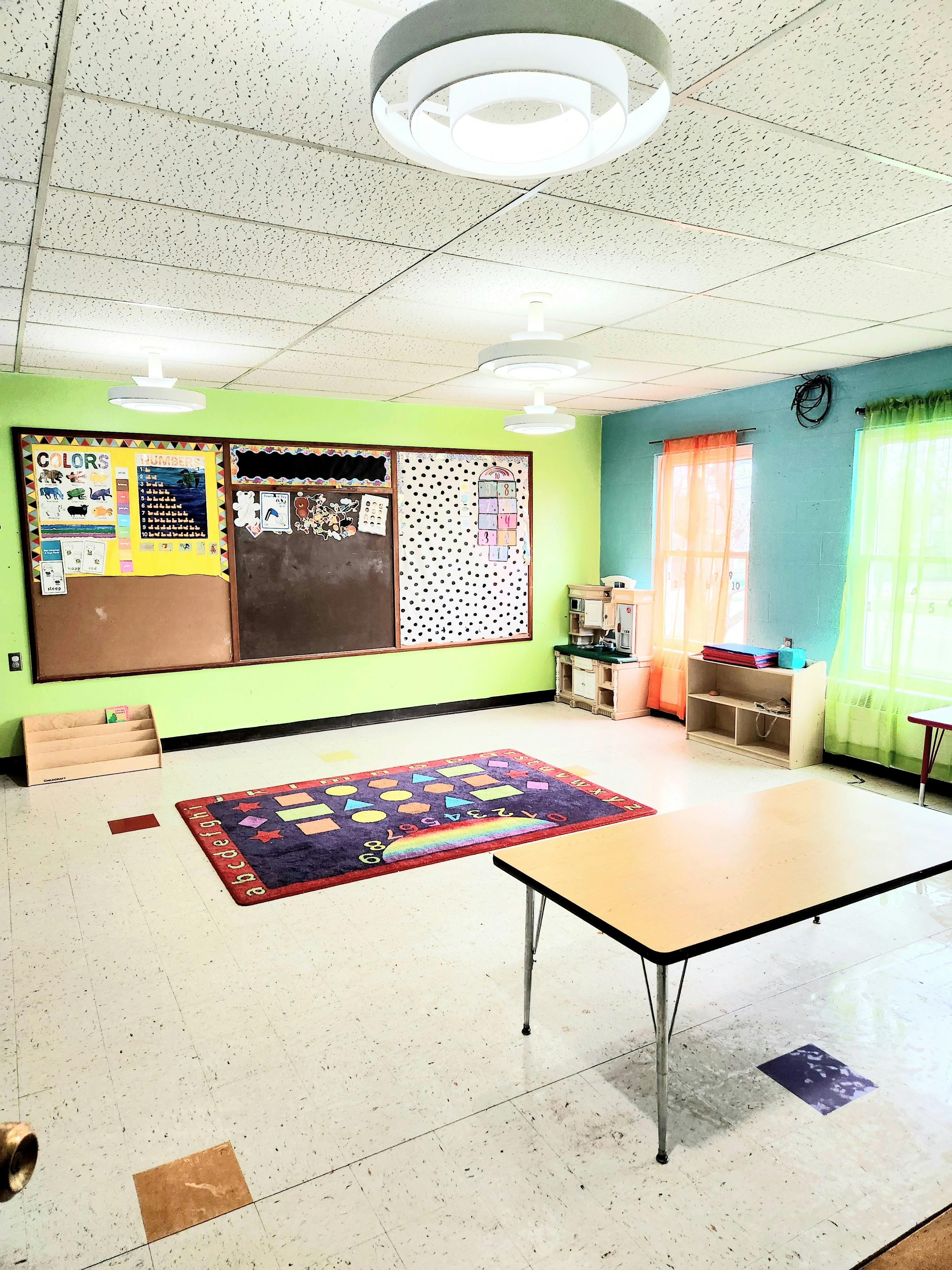 Classroom with bulletin boards, rug, and tables