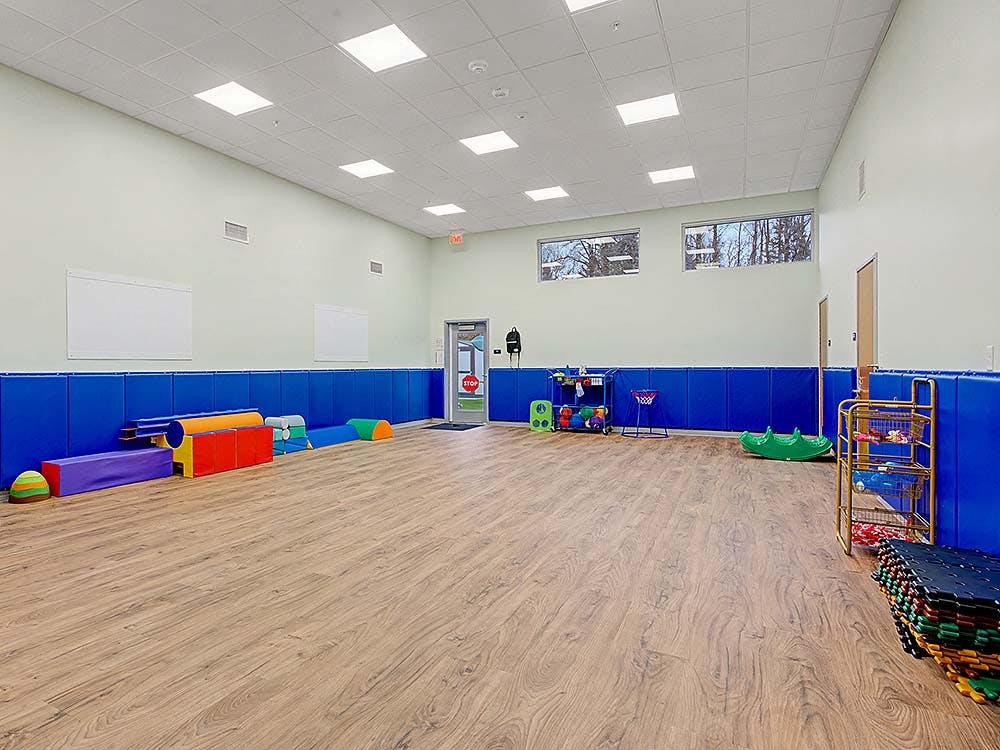 Indoor playroom with colorful play equipment and blue wall padding