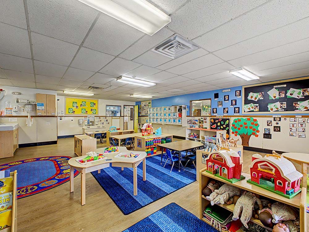 An empty early childhood classroom with toys and tables