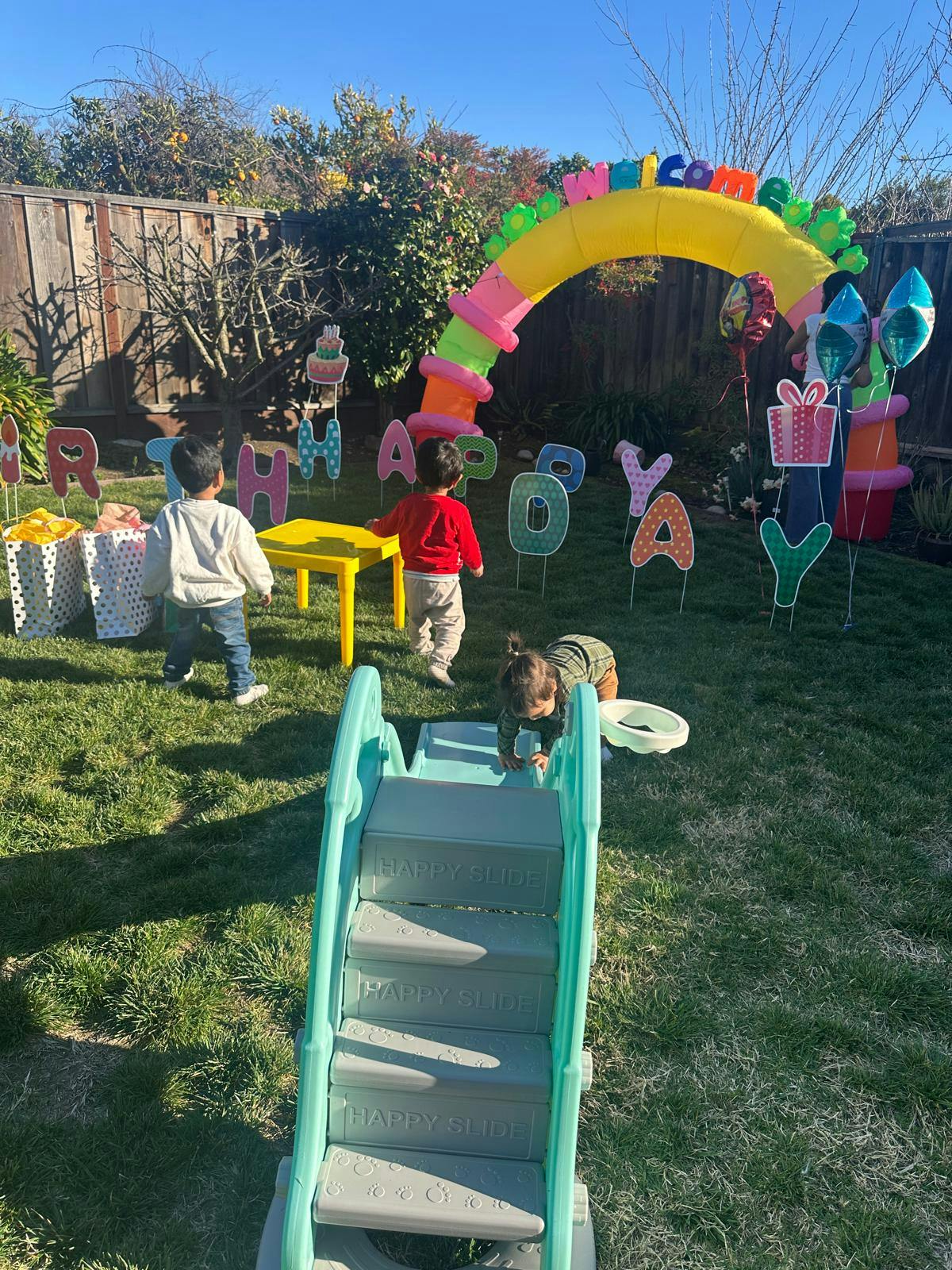 Children playing in a yard with a slide and colorful decorations