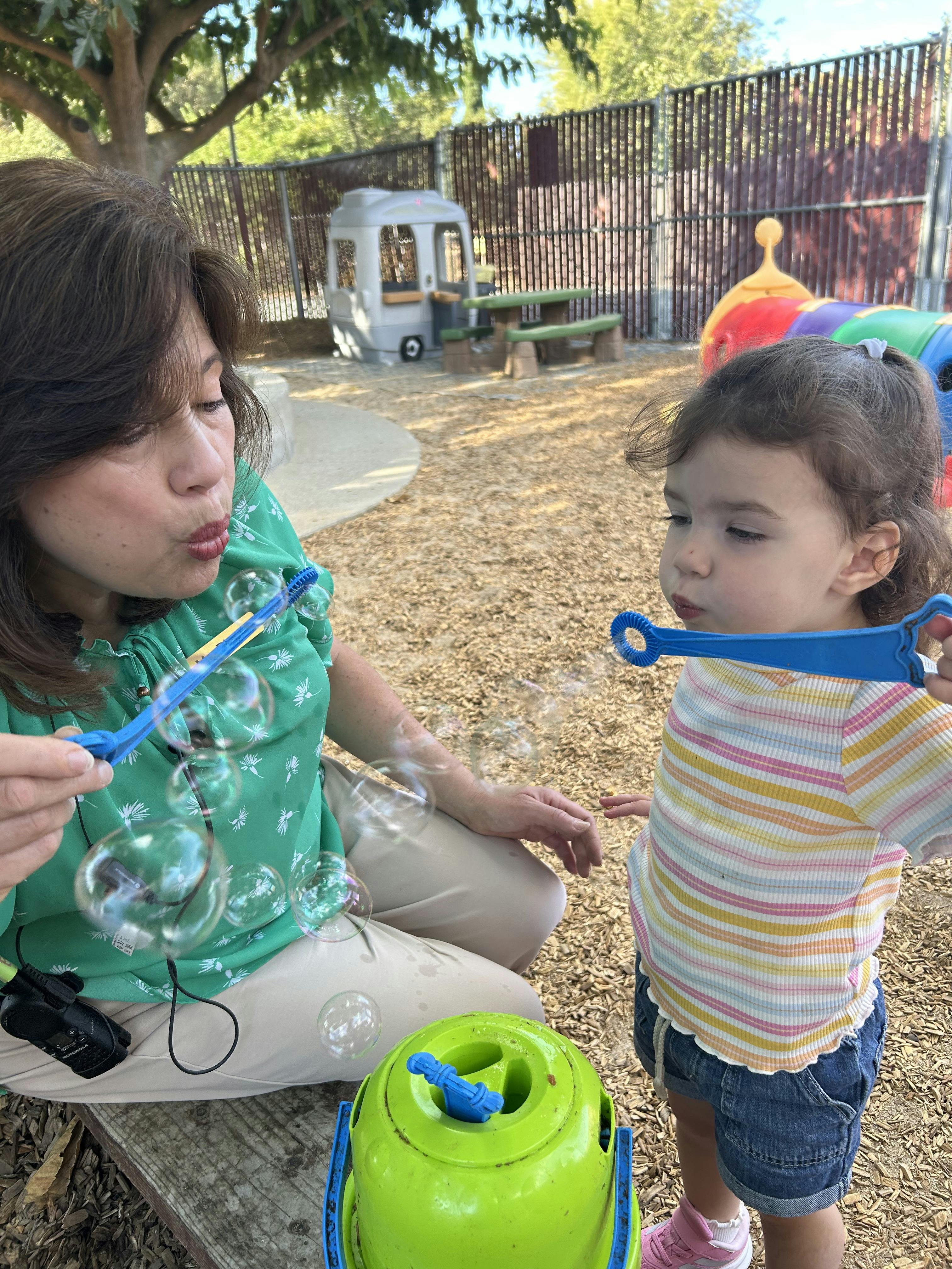 Adult and child blowing bubbles together on a playground