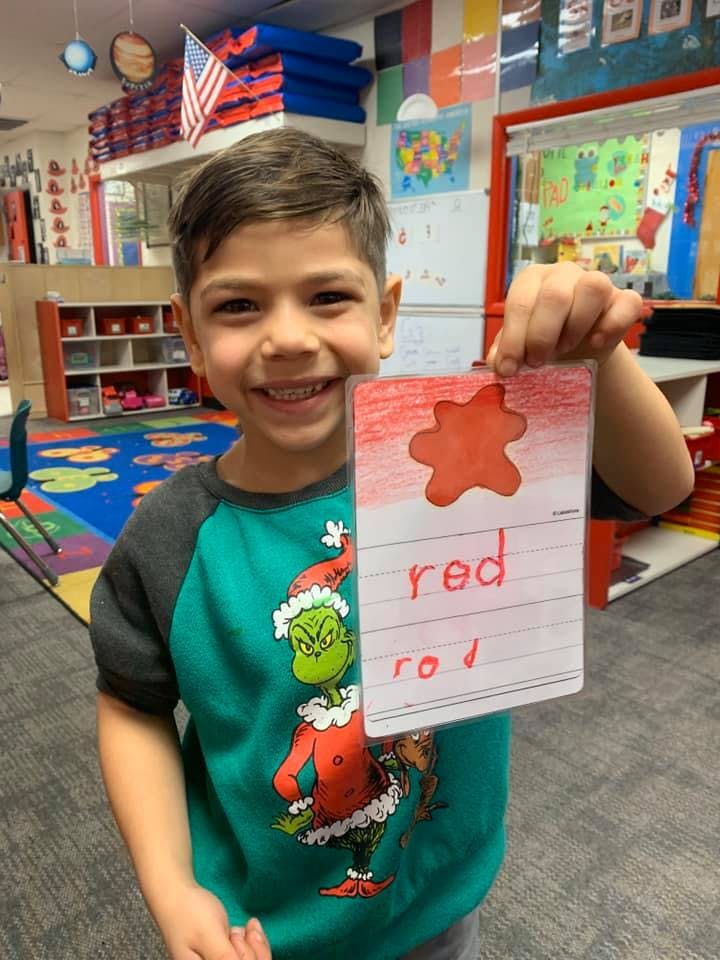 Child holding up a card with the word "red" written on it