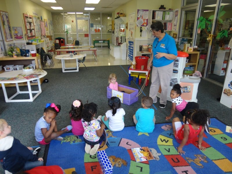 Adult supervising children playing on a rug in a classroom