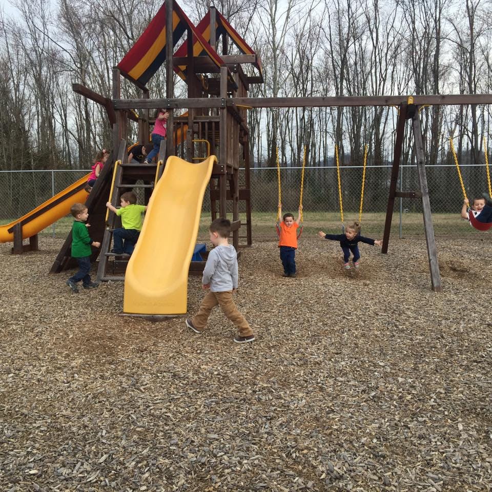 Children playing on a playground structure with slides and swings
