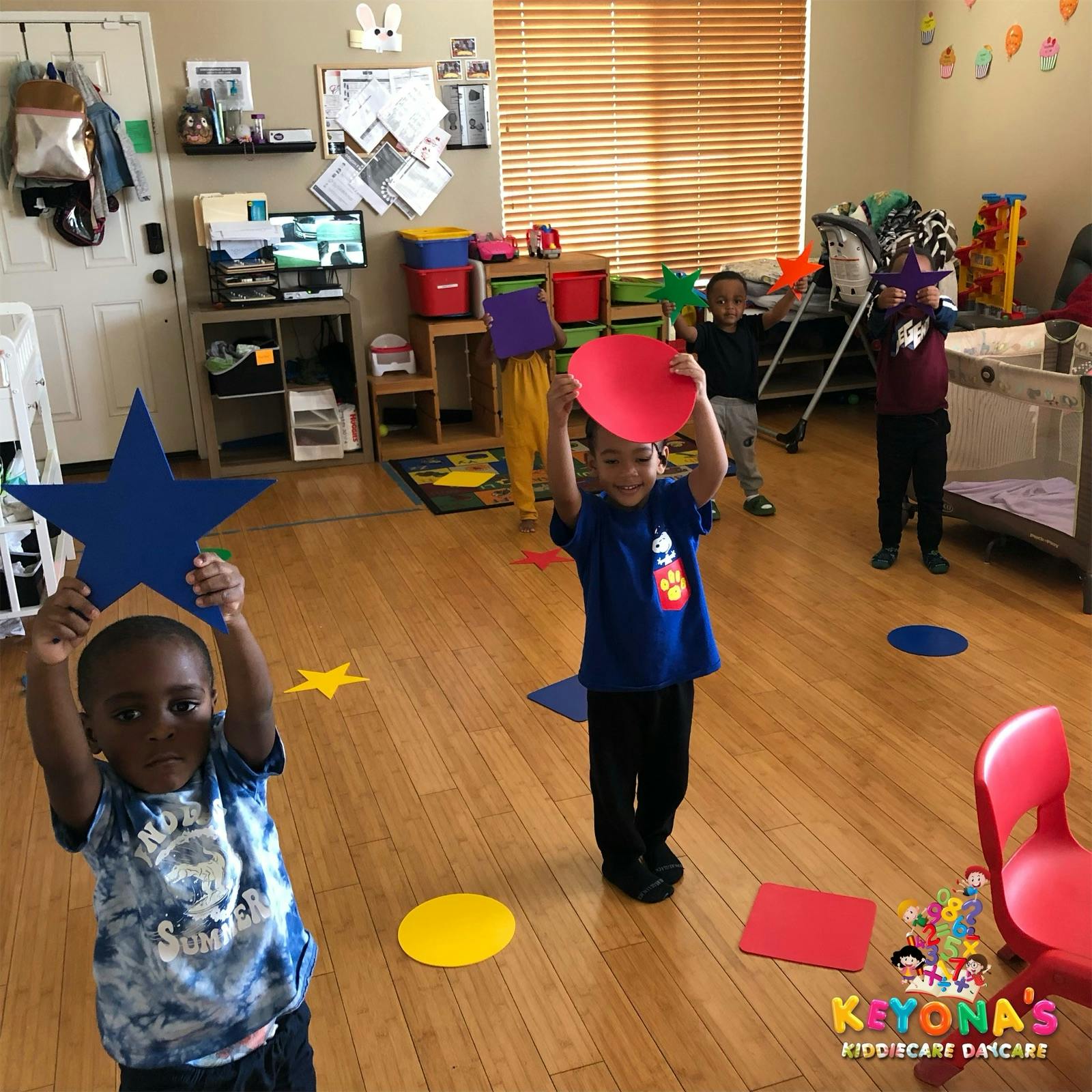 Children holding up large paper shapes in a classroom