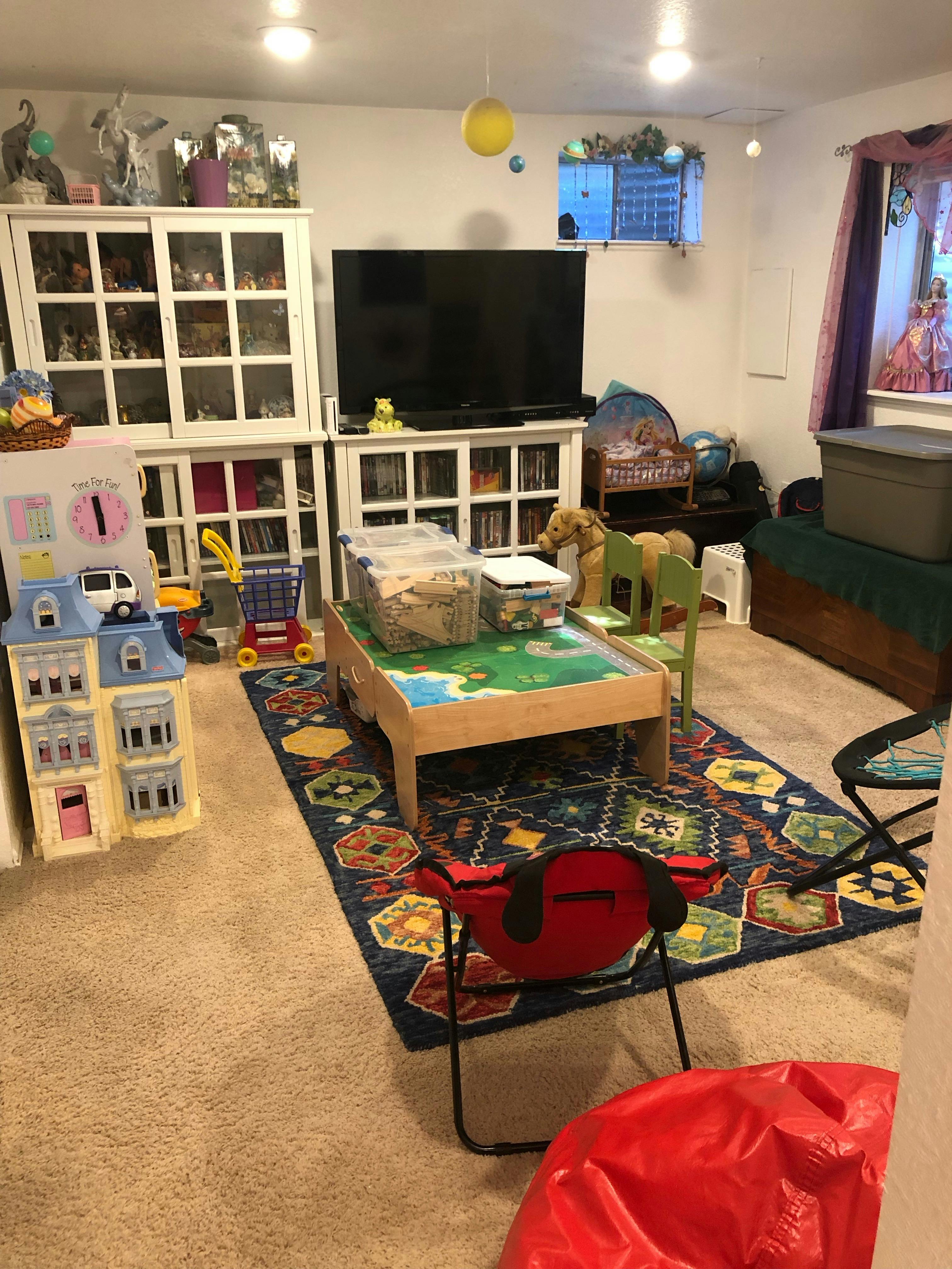 Playroom with a dollhouse, toy shopping cart, and activity table