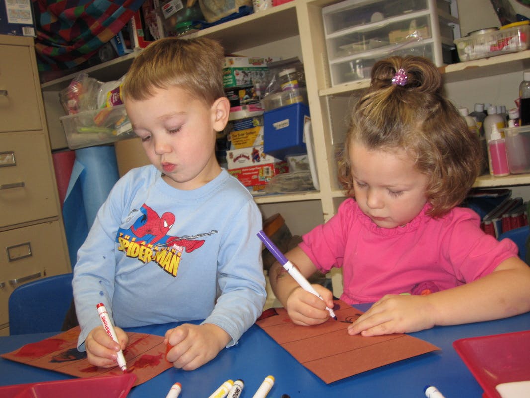 Two children drawing with markers on paper