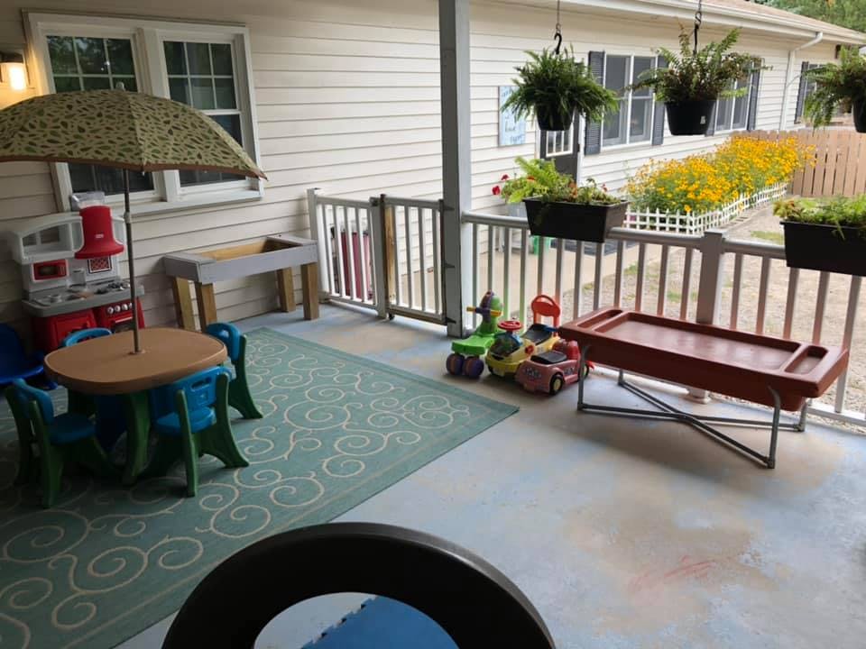 Patio with a small table and chairs, toys, and hanging plants