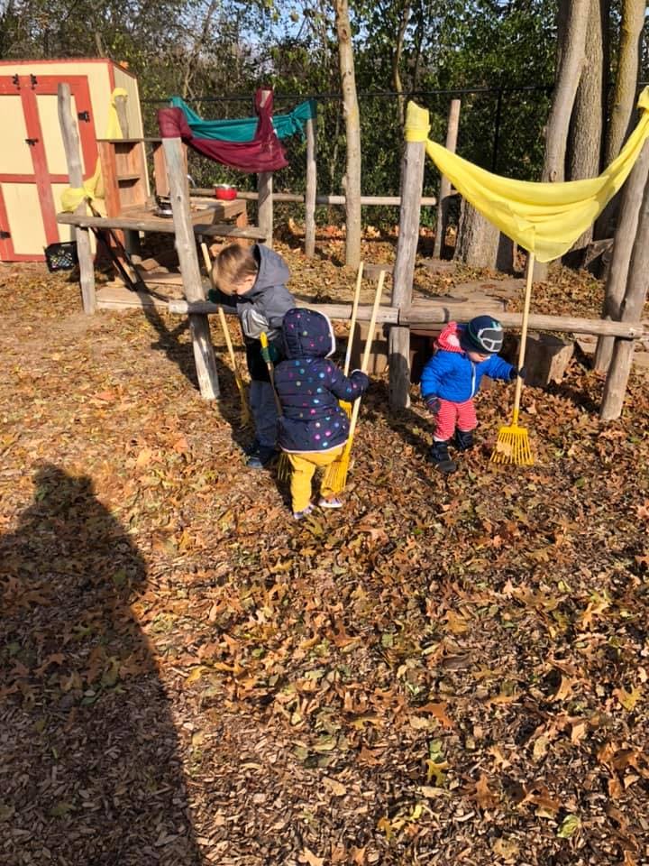 Adult and two children raking leaves outdoors