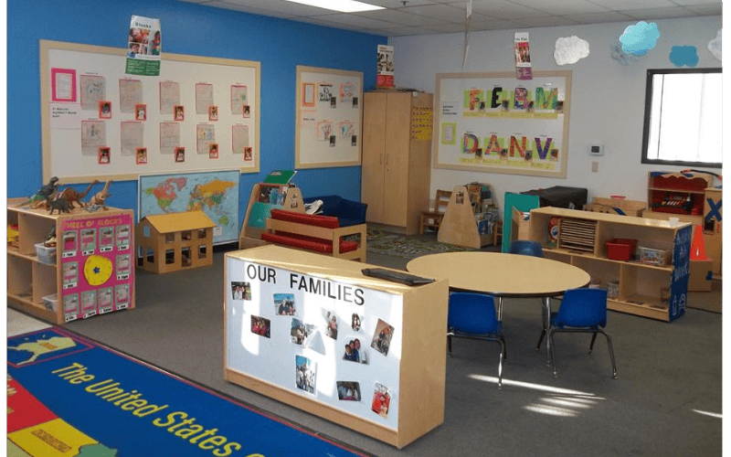Classroom with child-sized furniture, shelves of toys, and bulletin boards