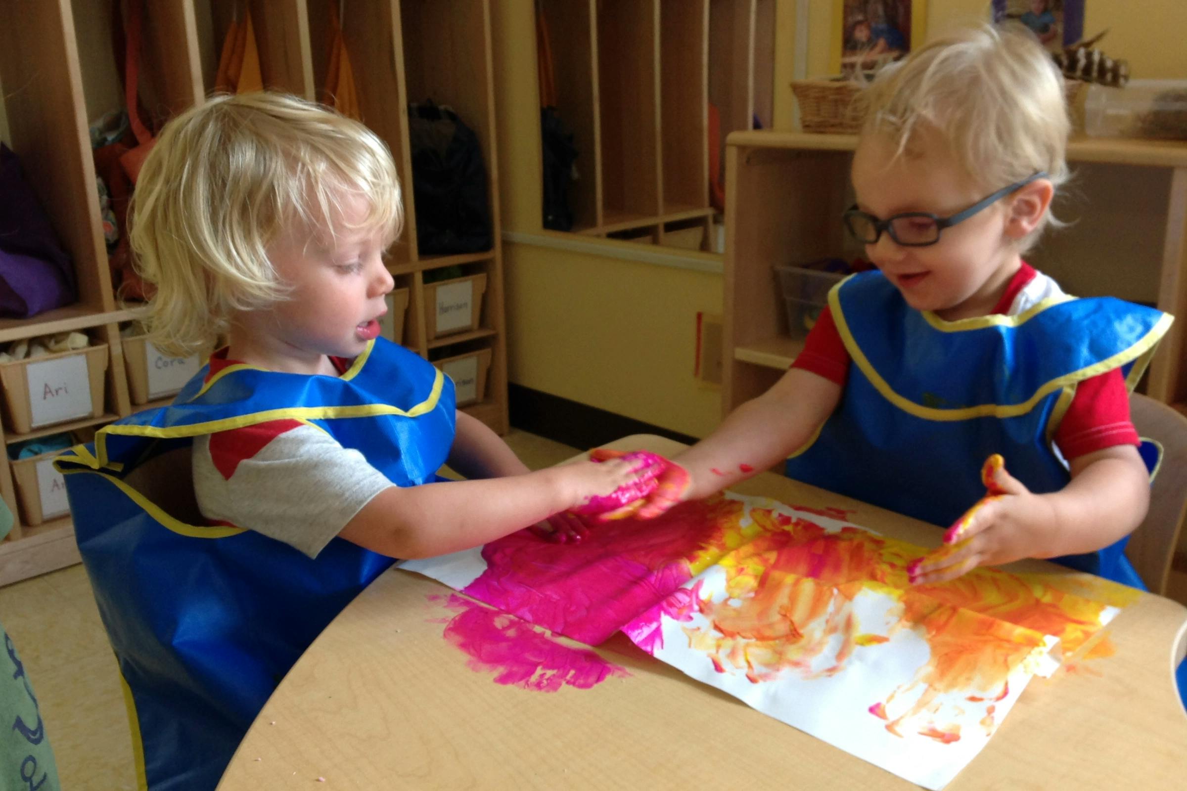 Two children finger painting at a table