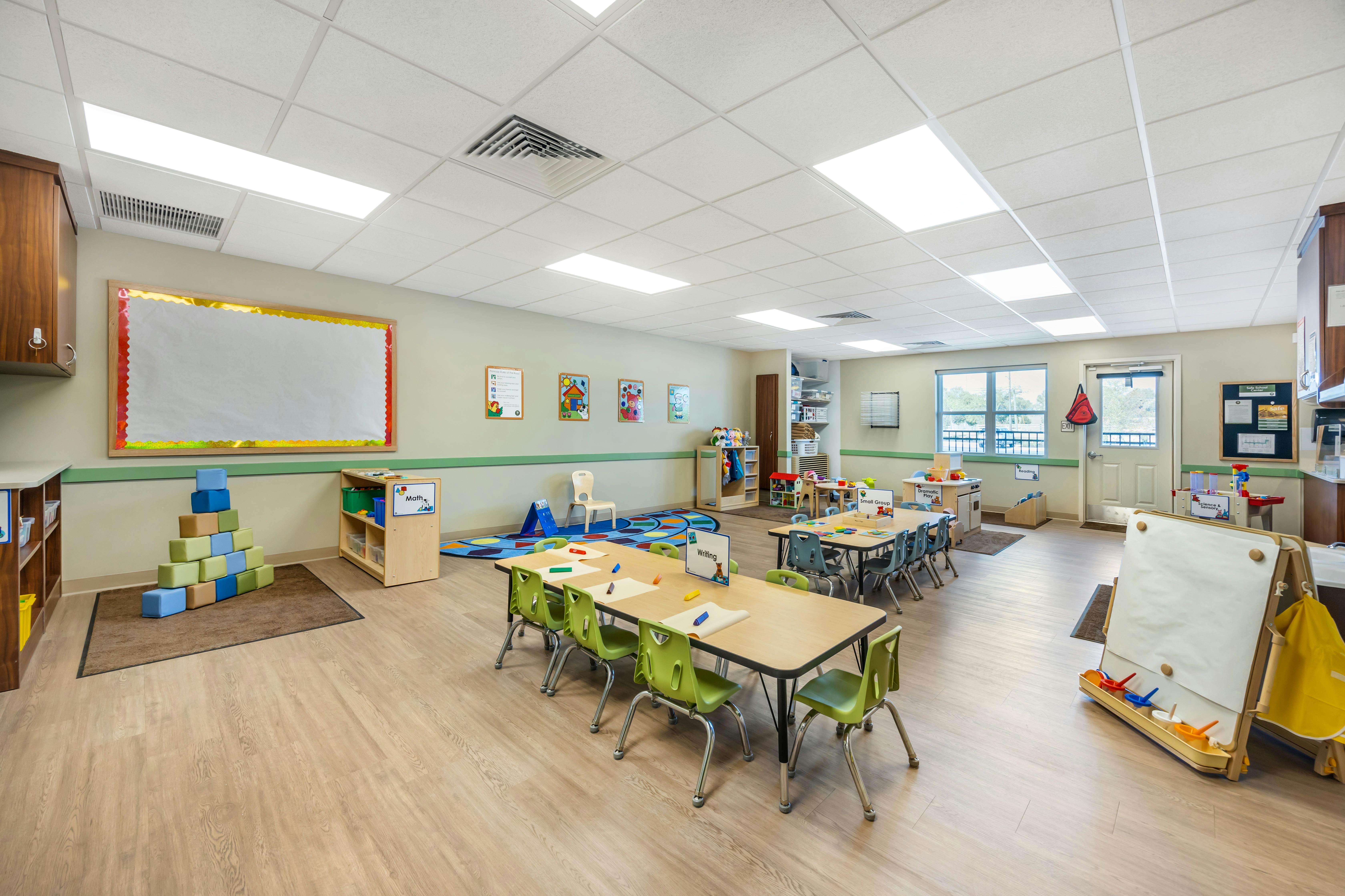 Classroom with tables, chairs, colorful rug, and children's toys