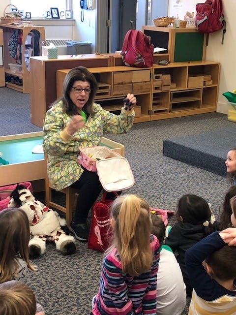 Adult speaking to children sitting on the floor in a classroom